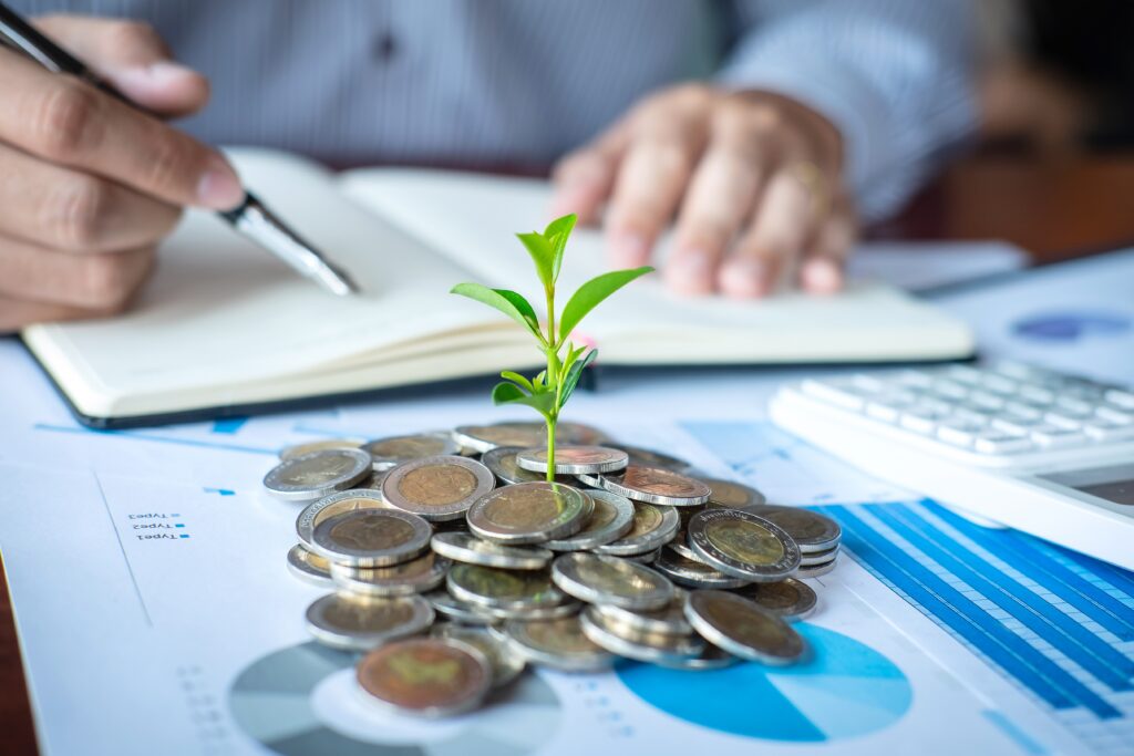 Man filing paperwork for investments with pile of growing pile of money with a plant.