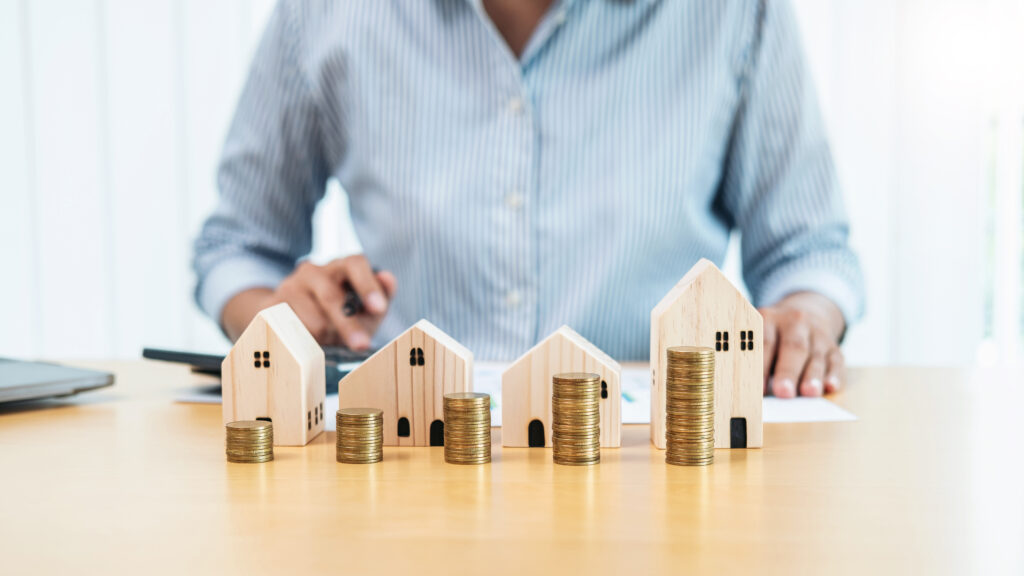 Person sitting behind a row of model buildings that represent investments.