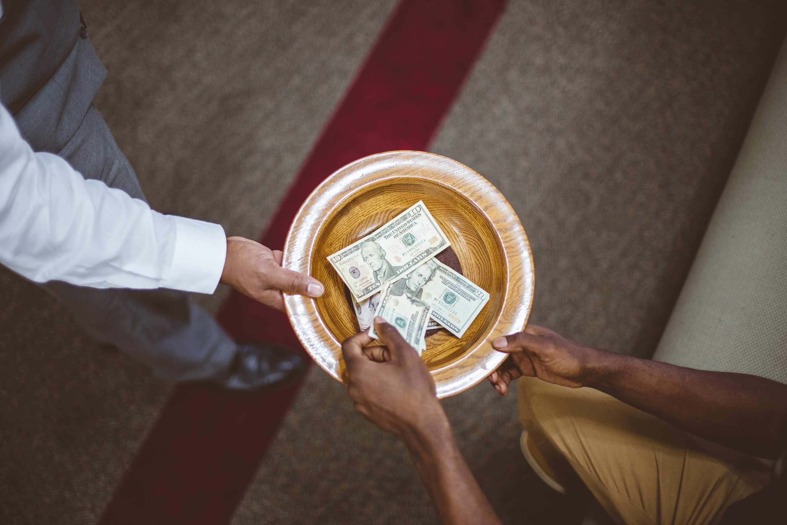 Overhead shot of a person collecting donations for the church with a blurred background.