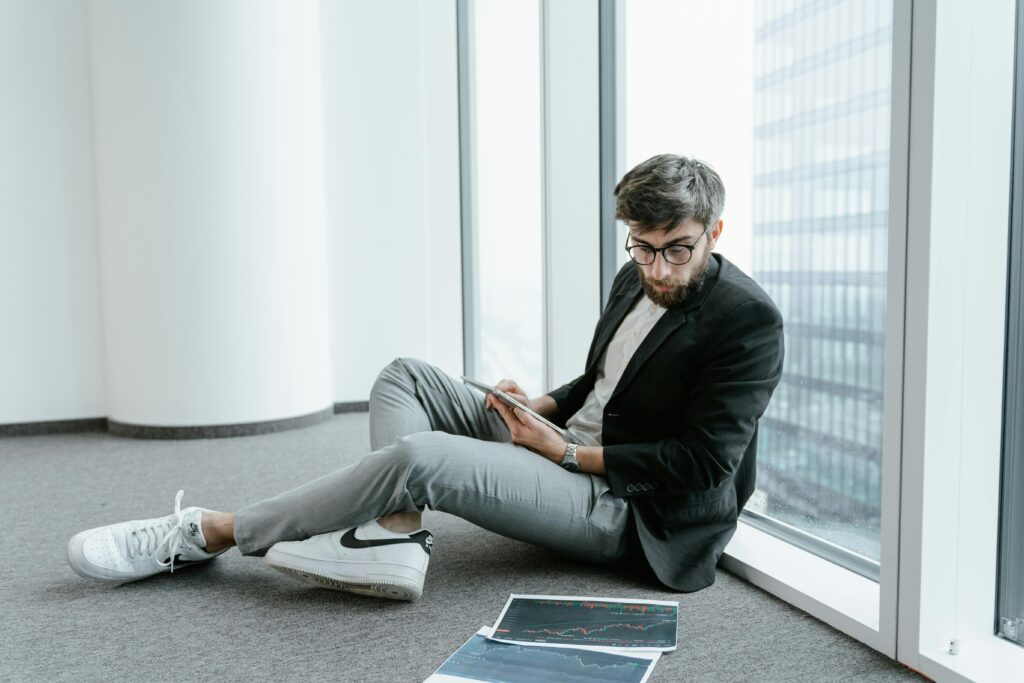 Man sitting on the ground looking over investment documents.